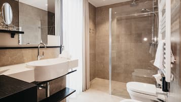 Un bagno moderno con un lavandino ampio, uno specchio e una cabina doccia.