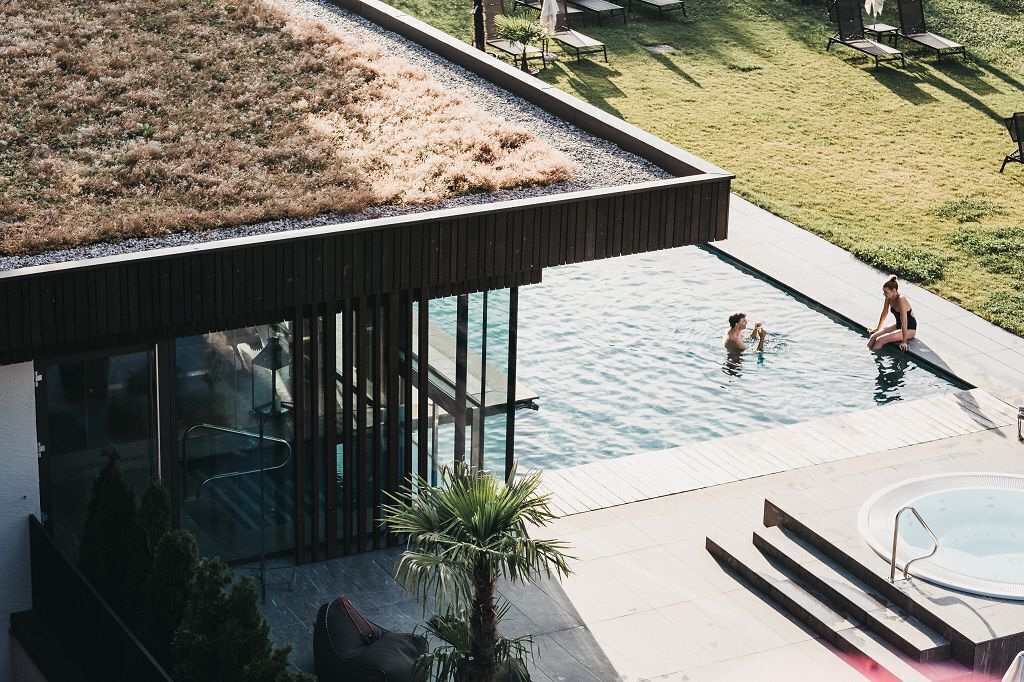 Un edificio moderno con jardín en la azotea, piscina y jacuzzi.