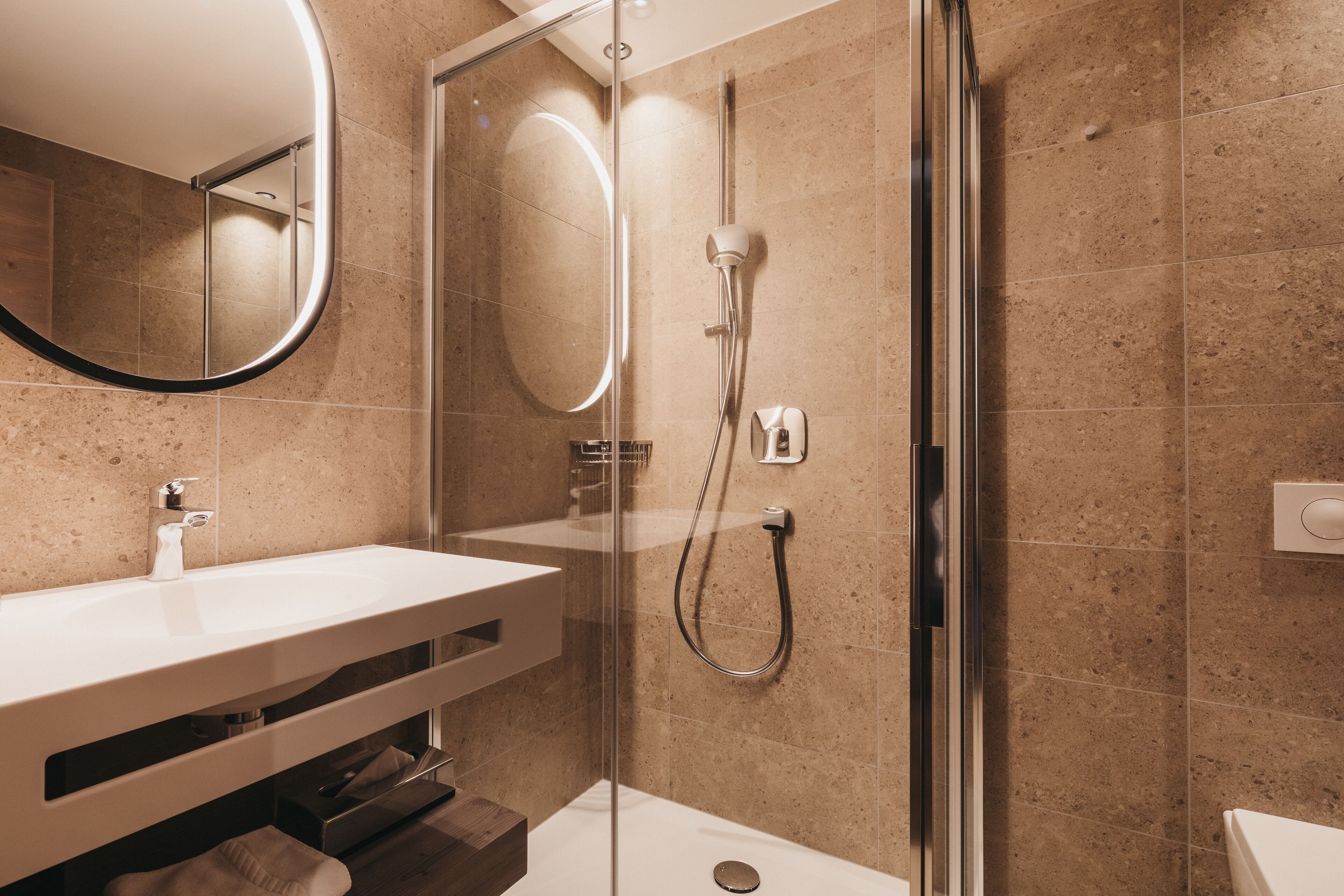 A modern bathroom with a glass-enclosed shower, a white sink, and a mirror.