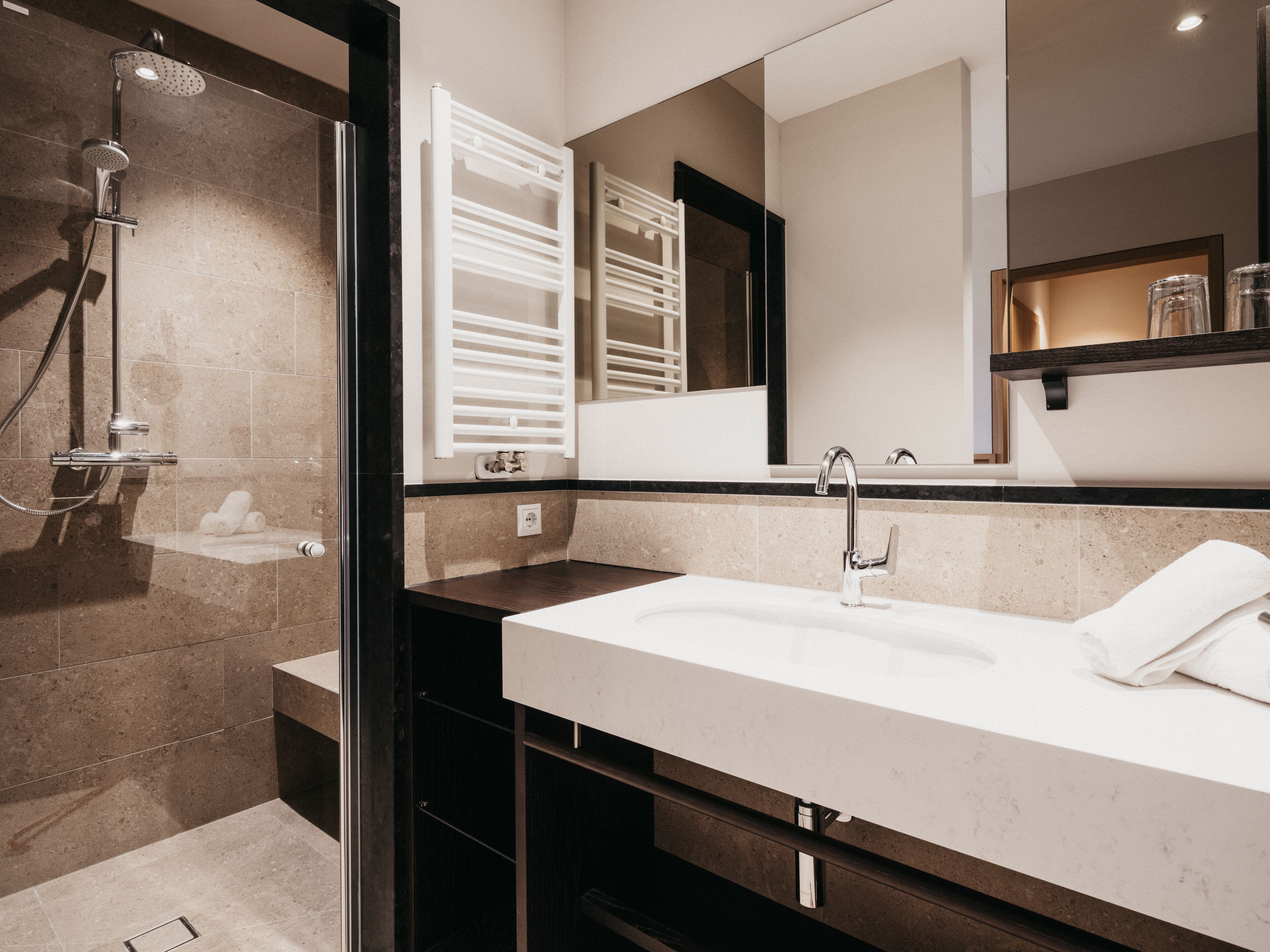 Un bagno moderno con doccia vetrata, un lavandino capiente e uno specchio sopra.