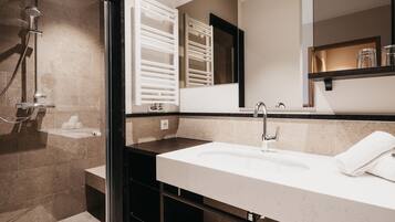Un bagno moderno con doccia vetrata, un lavandino capiente e uno specchio sopra.