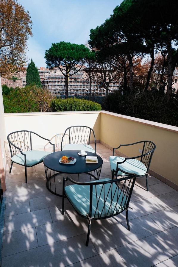 A terrace with a round table and four chairs, a plate with food, and a book. - Hotel Vittoria (Pompei)