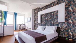 A modern hotel room with a large bed, a desk, and a dining area. - Mini Hotel (Pozzuoli)