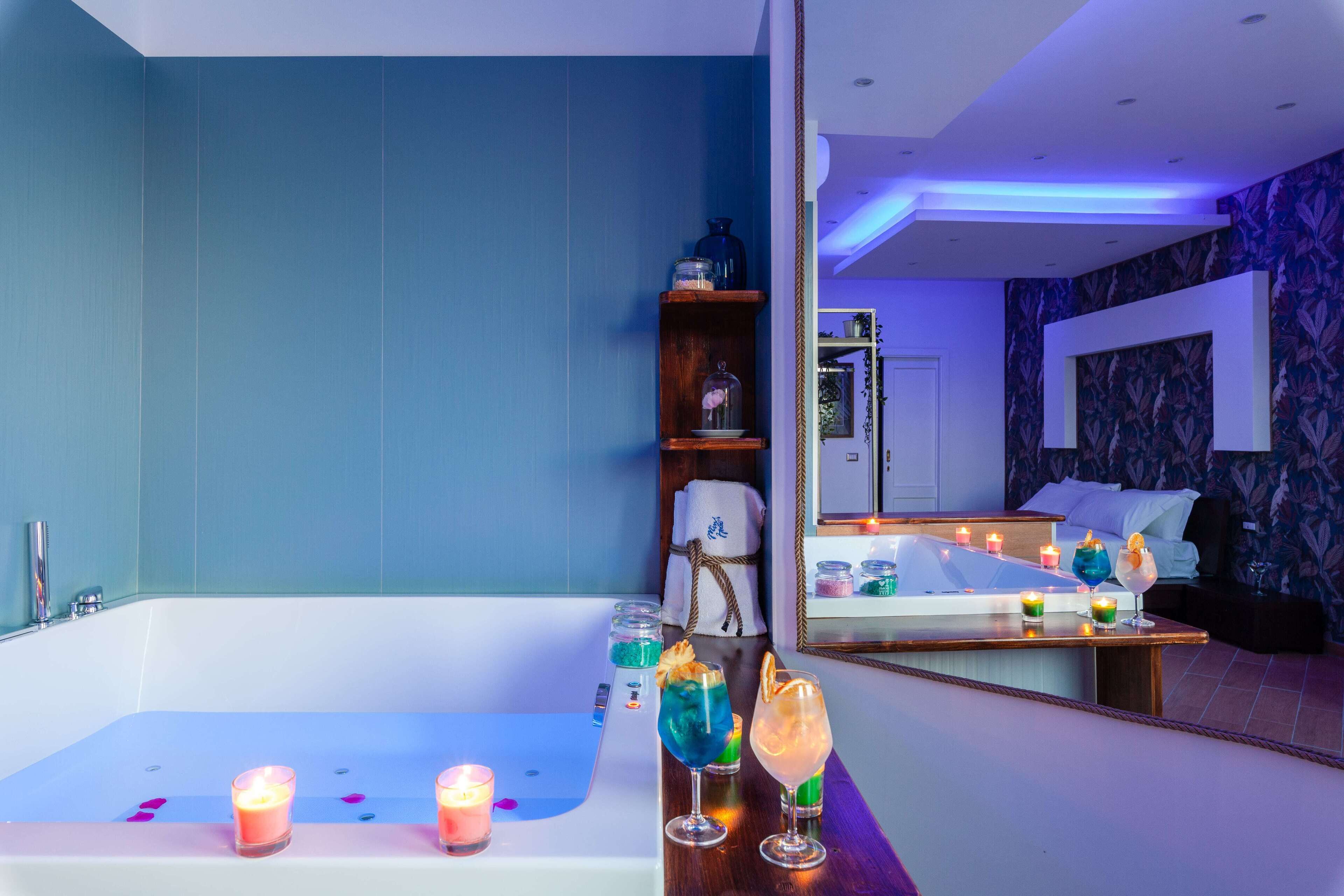 Un baño moderno con bañera, tocador con espejo y repisa con velas y objetos decorativos.
