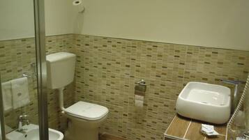Un baño con inodoro, bidé, lavamanos y zona de ducha.