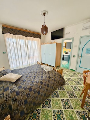 A bedroom with a bed, a wardrobe, a television, and a view into the kitchen. - Riviera B&B Rooms and Apartament SEA-VIEW (Maiori)