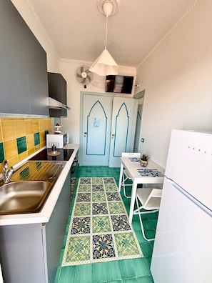A compact kitchen with a sink, stove, and a small dining table. - Riviera B&B Rooms and Apartament SEA-VIEW (Maiori)