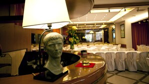Ein Hotel-Empfangsbereich mit einem Schreibtisch, einer Büste, einer Lampe und einer Blumenkomposition.