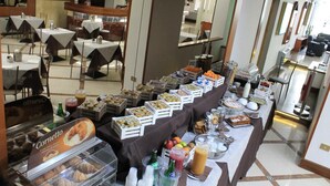 Ein Buffet mit verschiedenen Speisen und Getränken, darunter à la carte Menüs, Obst und eine Vitrine mit Backwaren.