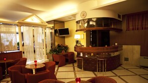 Eine Hotelhalle mit Empfangstresen, Sitzgelegenheiten und einer Wanduhr.