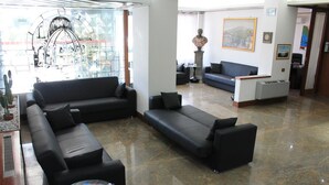 Eine großzügige Lobby mit schwarzen Ledersofas, einem Empfangstresen und einem großen Fenster mit einem Buntglas-Design.