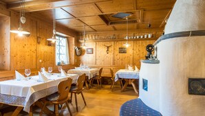 A restaurant with wooden walls, white tables, and hanging lights. - Gissbach (Brunico)