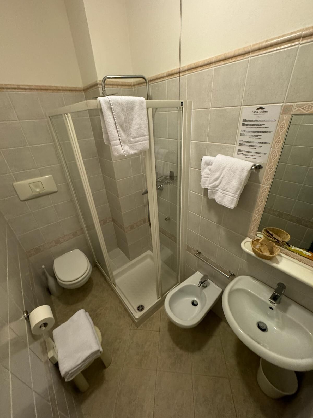 A bathroom with a glass-enclosed shower, a toilet, a bidet, and a sink.
