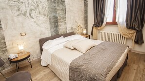 Un dormitorio con cama, mesita de noche con lámpara, una silla y un radiador.