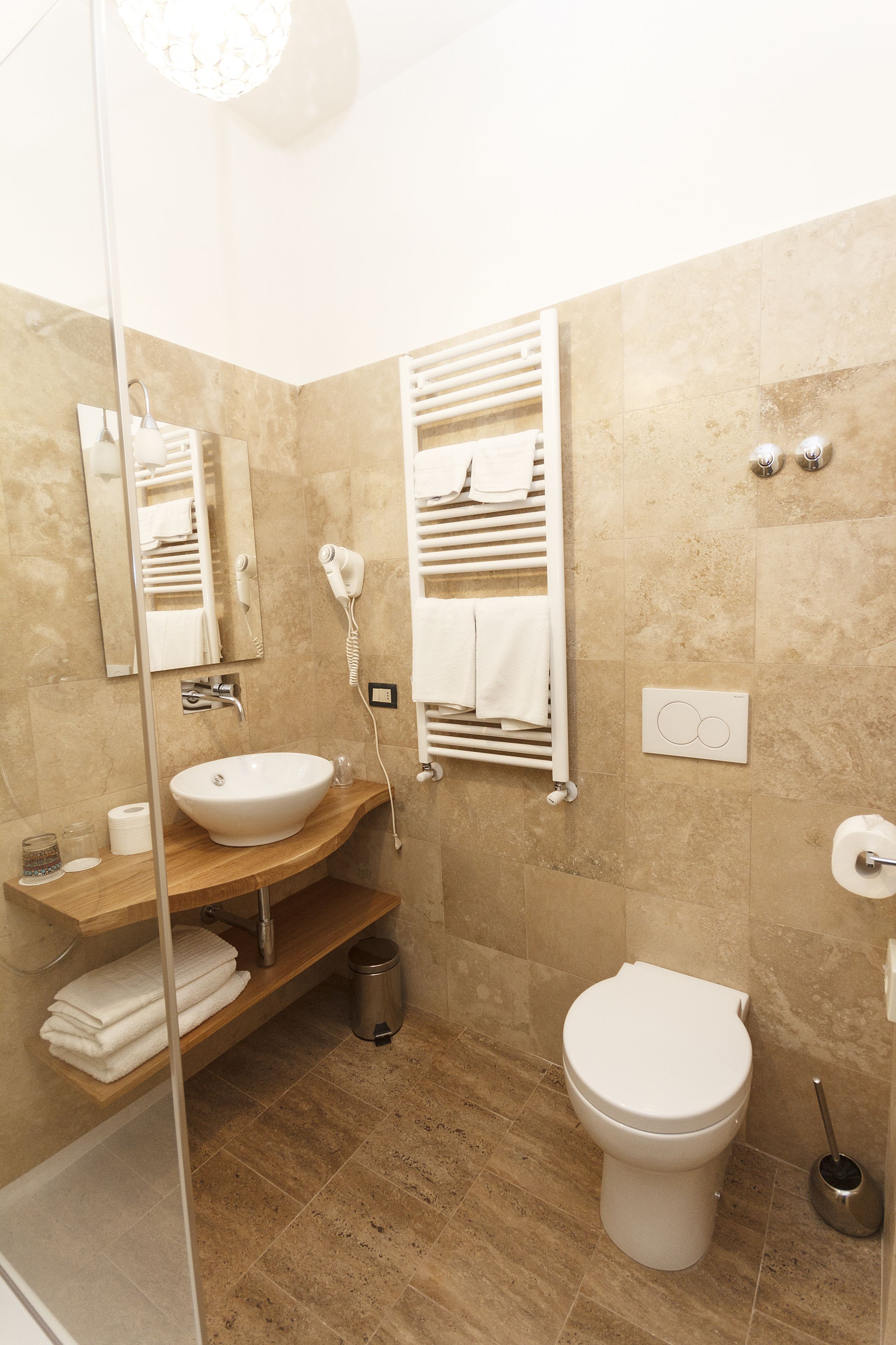 A bathroom with a sink, mirror, towel rack, toilet, and shower.
