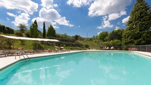 Una piscina cristalina con sillas de descanso y una pérgola.