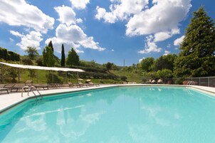 Una piscina al aire libre, sillones reclinables de piscina