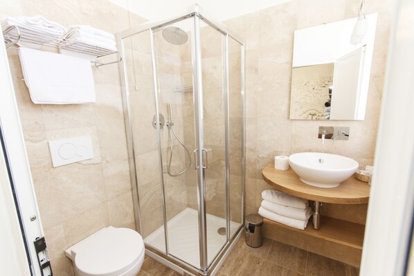 Un baño moderno con ducha de vidrio, lavamanos blanco y retrete.