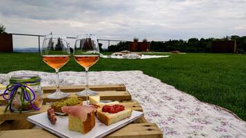 A picnic setup with food and drinks on a wooden table outdoors.
