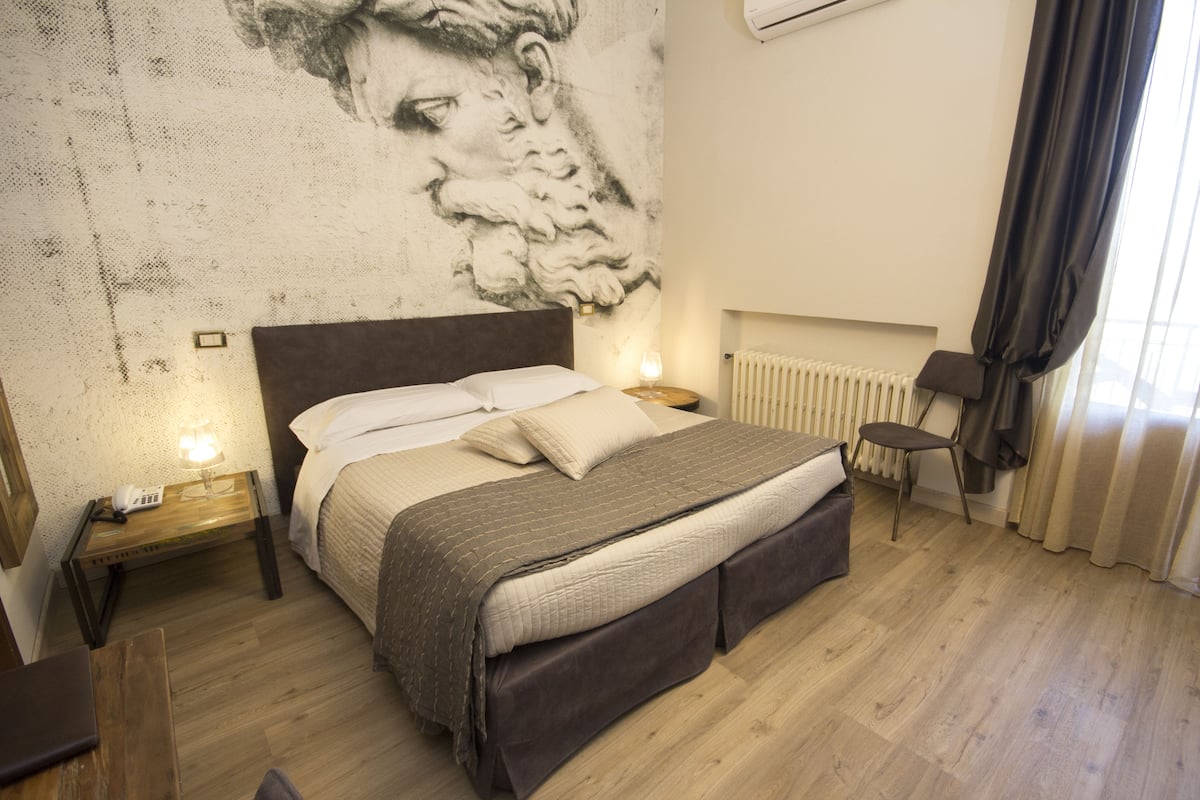 Une chambre à coucher comprenant un lit, des tables de chevet, une chaise et une décoration murale.