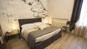 A bedroom with a bed, bedside tables, a chair, and a wall mural.