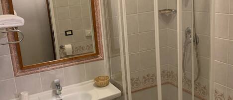 A bathroom with a sink, mirror, shower, and bidet.
