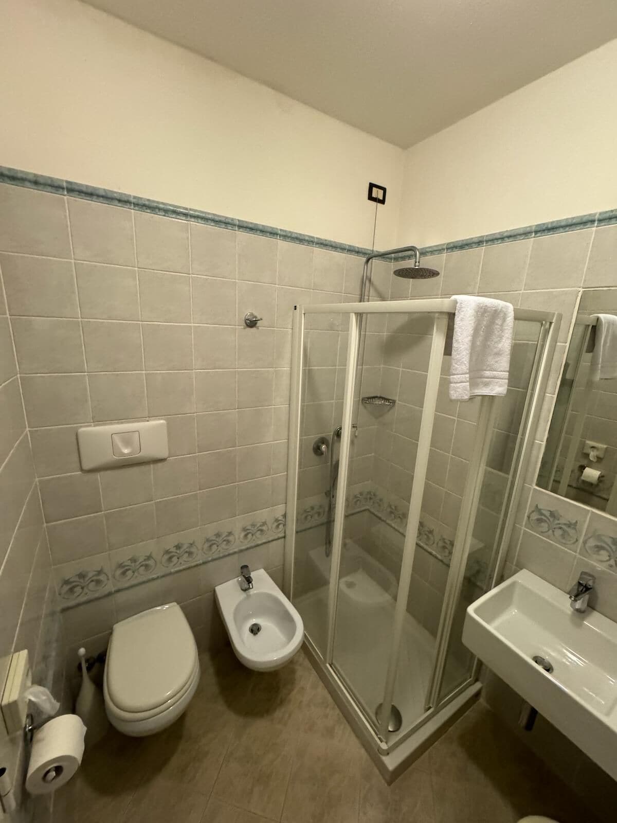Un baño con ducha envuelta en vidrio, inodoro, bidé y lavamanos.