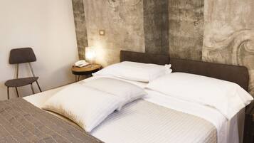 A neatly made bed with white linens, a wooden headboard, and a small bedside table with a lamp.