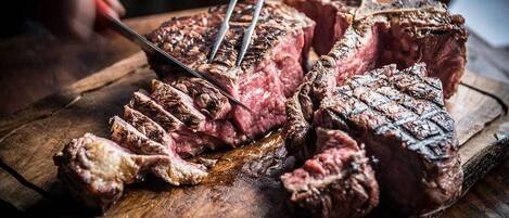 A steak being sliced on a wooden cutting board.
