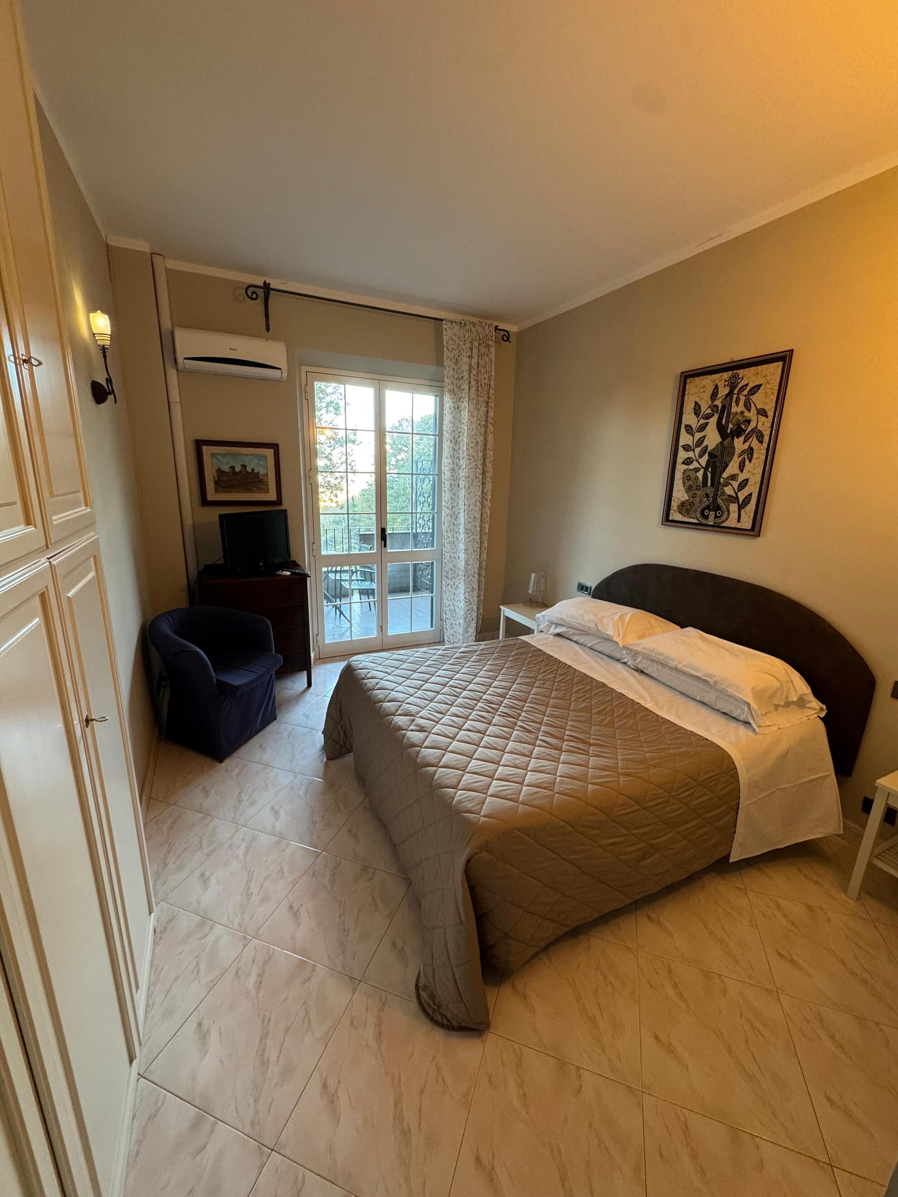 Une chambre à coucher avec un lit, une chaise, un bureau et une fenêtre donnant sur des arbres.