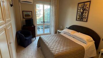 Une chambre à coucher avec un lit, une chaise, un bureau et une fenêtre donnant sur des arbres.