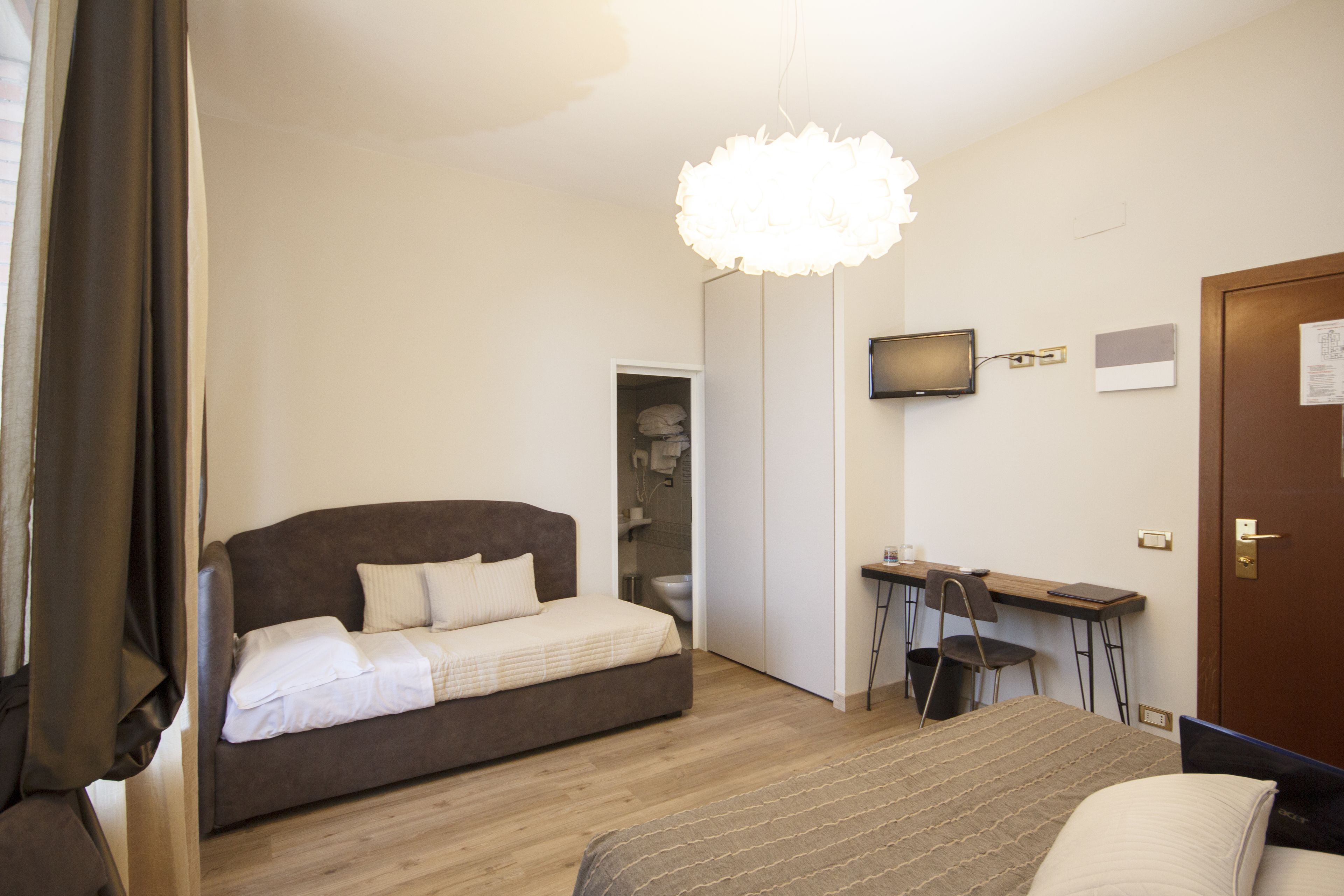 Una camera da letto con un letto, una scrivania, una sedia, una televisione e una porta.