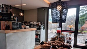 Un café con barra, máquina de café y vistas al exterior.