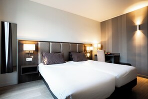 A modern hotel room with a large bed, two bedside tables with lamps, a nightstand, and a wall-mounted light fixture. - Hôtel de Flore - Montmartre (Paris)