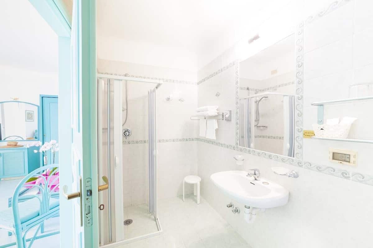 A bathroom with a glass shower enclosure, a white sink, and a vanity with a mirror.