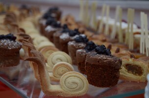 Variedad de pasteles exhibidos en un mostrador de vidrio.