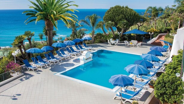 A pool area with lounge chairs and umbrellas, overlooking a clear blue sea. - Hotel Capizzo (Forio)
