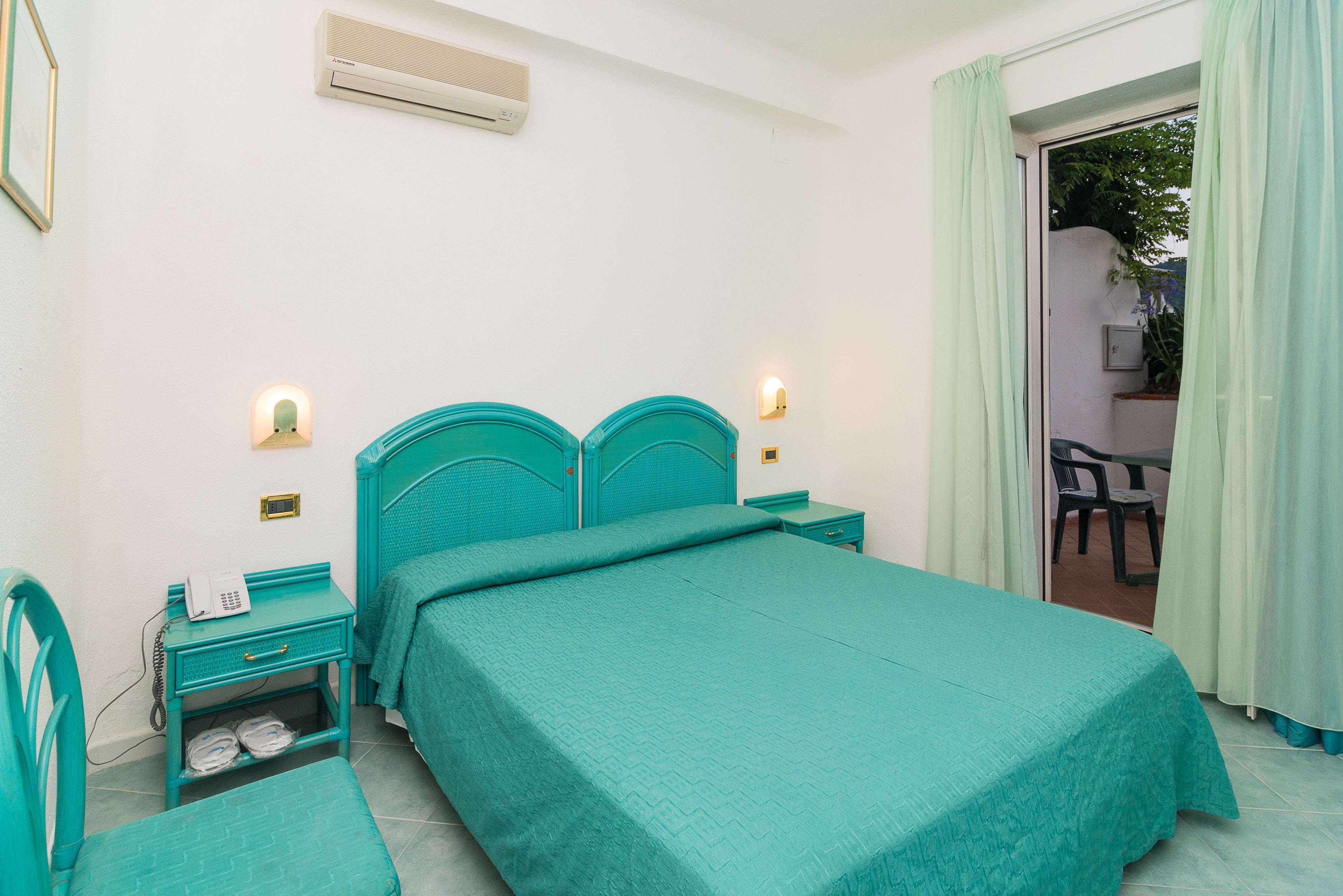 A bedroom with a bed, a nightstand, a chair, and a small table.