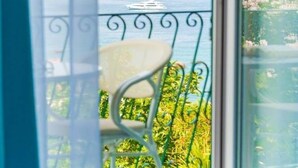A window with a view of a balcony, a chair, and a hat on the windowsill. - Hotel Capizzo (Forio)