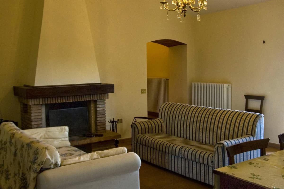 Una sala de estar con chimenea, sofá a rayas y una mesa de comedor.