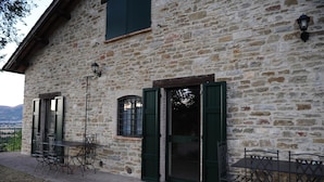 Un edificio de piedra con un patio que ofrece mobiliario exterior y vistas al campo.