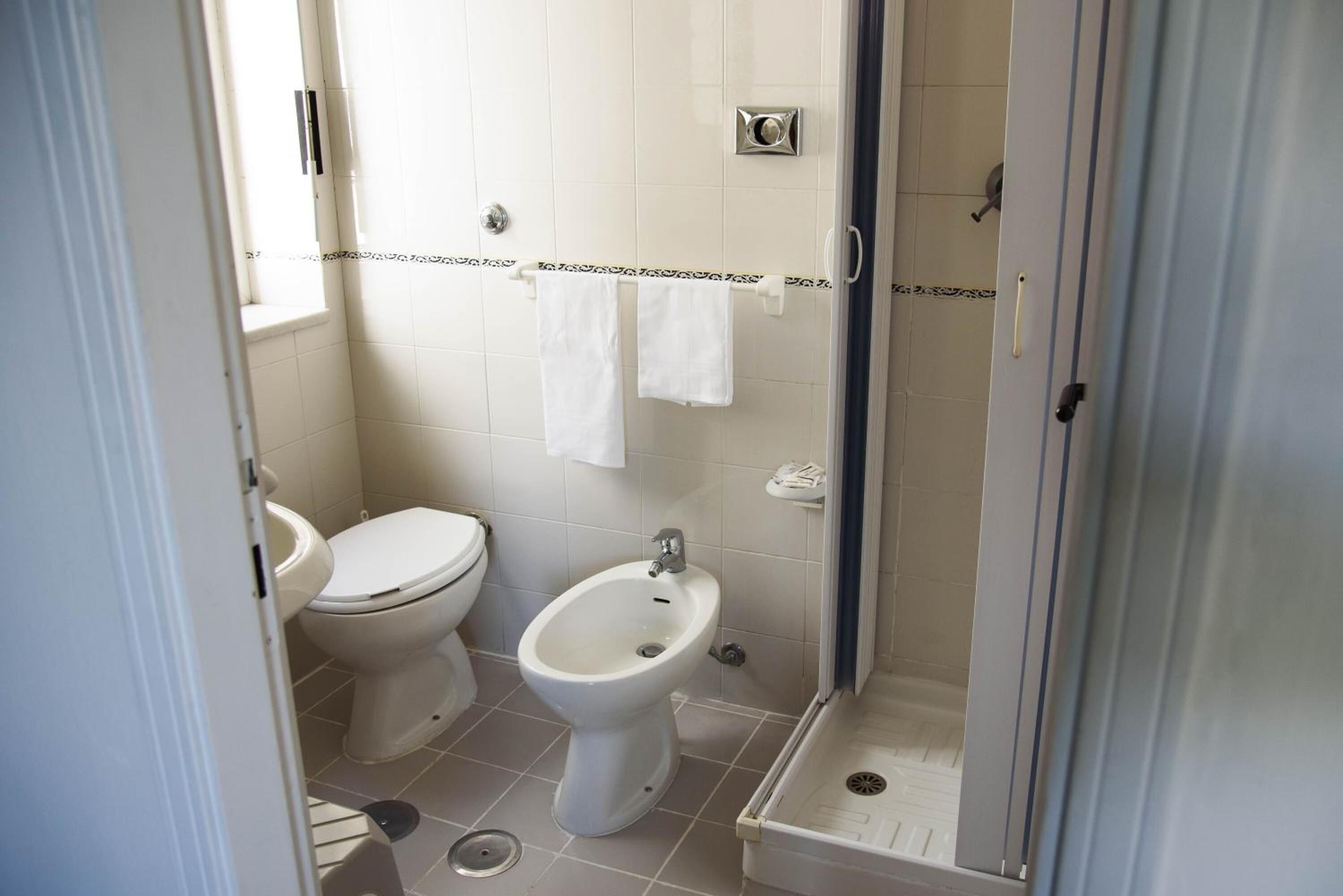 A bathroom with a toilet, bidet, and shower.