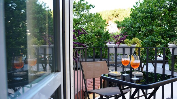 A balcony with a table and chairs, two drinks, and potted plants. - Calypso (Pompei)