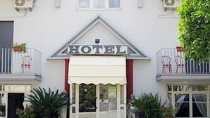 A hotel with a white facade, a 'HOTEL' sign above the entrance, and potted plants in front. - Calypso (Pompei)