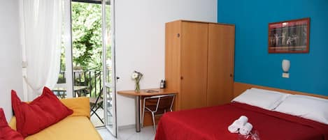 Quarto de hotel com cama, sofá, escrivaninha e guarda-roupa.