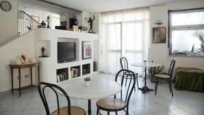 A spacious living area with a dining table, chairs, a TV, and a staircase. - Calypso (Pompei)