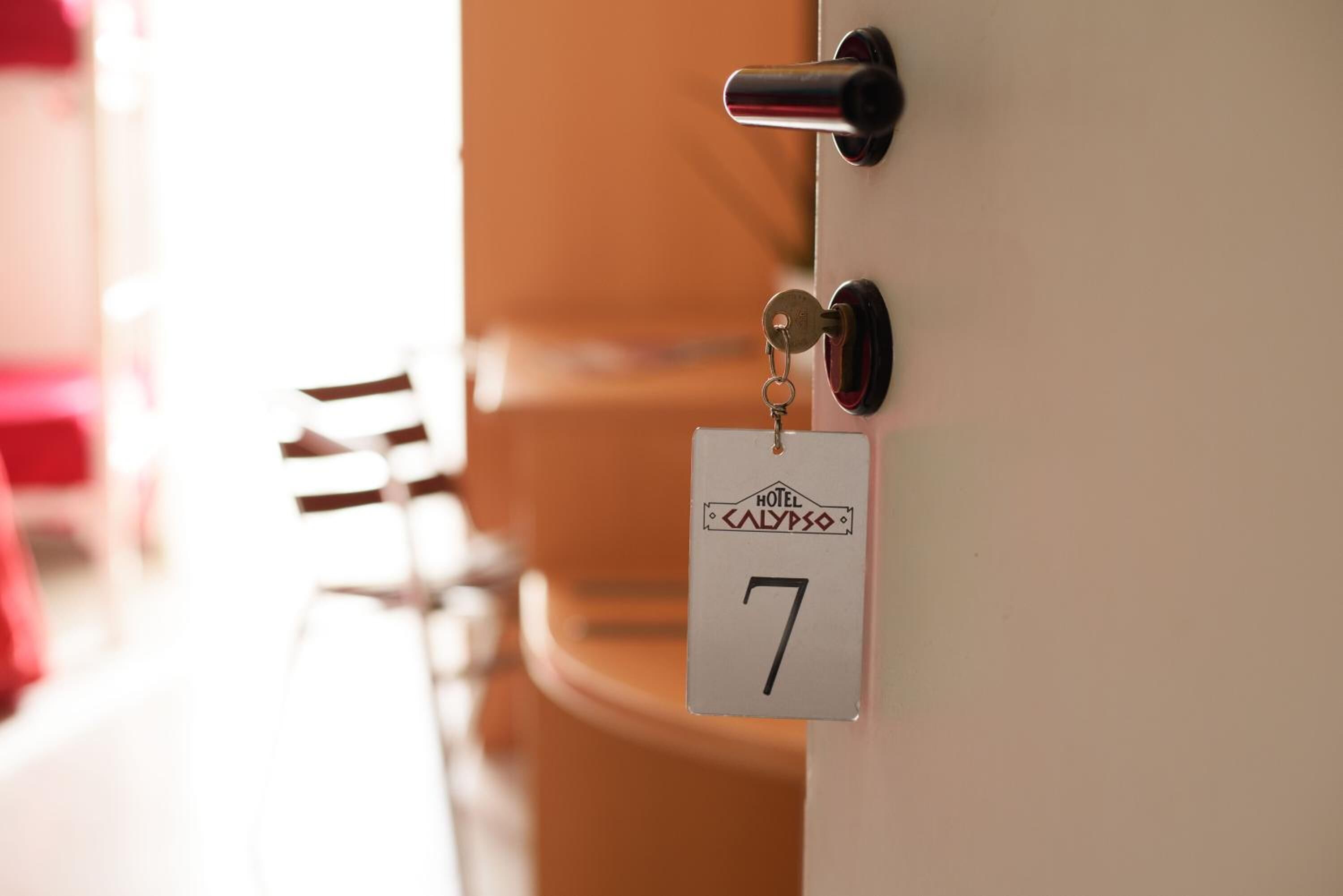 Puerta de habitación de hotel con un portachips que muestra el número 7 y el nombre HOTEL CALYPSO.