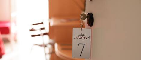 Puerta de habitación de hotel con un portachips que muestra el número 7 y el nombre HOTEL CALYPSO.