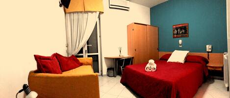 A hotel room with a bed, a sofa, a desk, and a wardrobe.
