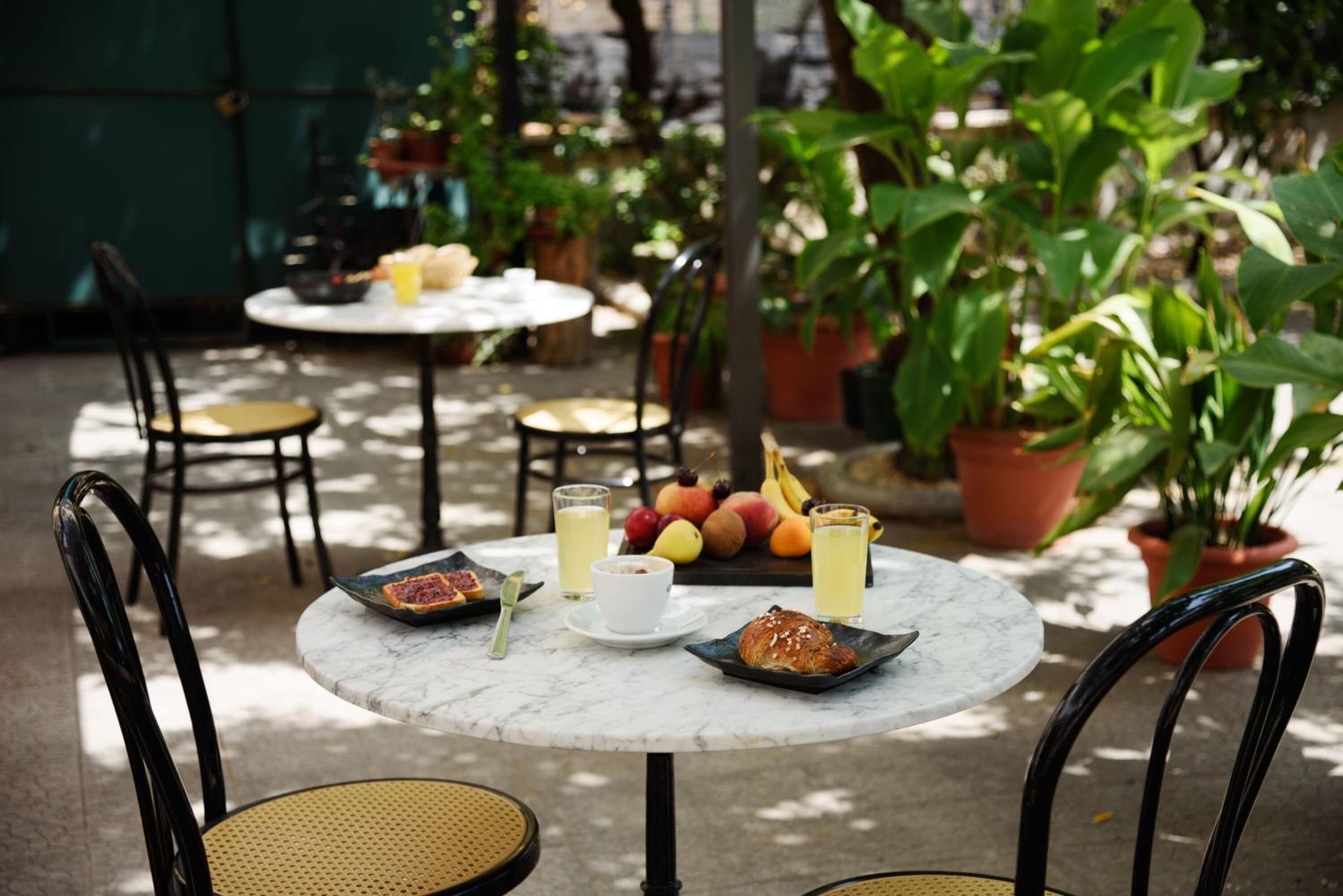 A round table with breakfast items including croissants, fruit, and beverages.